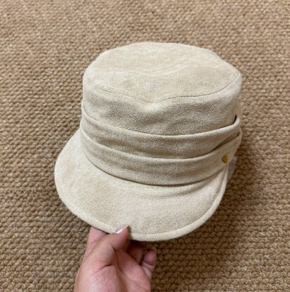 Gold heart charm on the side of a vegan suede flat cap, close view