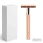 Rose gold double edge safety razor standing next to a plain white retail box