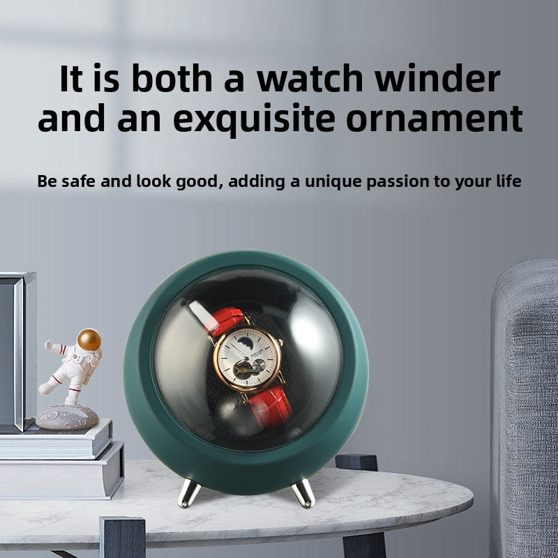 Emerald green watch winder used as a desk ornament on a marble table with books and a figurine