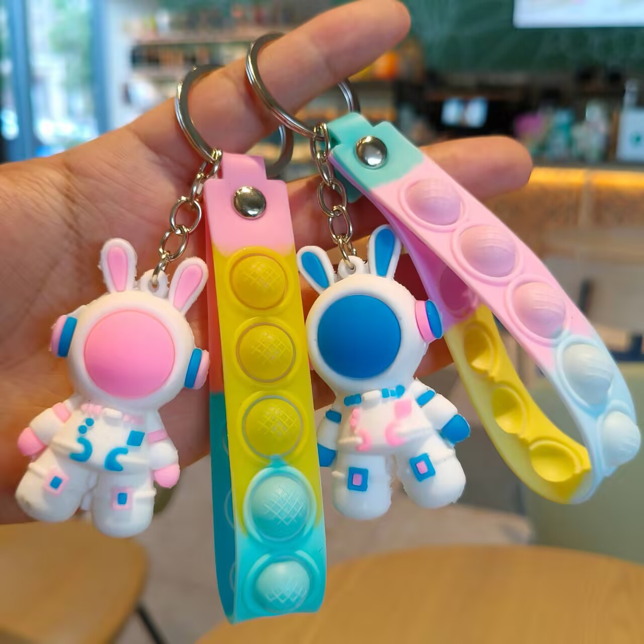 Astronaut rabbit charm linked by a metal split ring and short chain to a colorful push pop strap