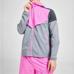 Man in a pink and grey colour block hooded sports jacket pulling the hood up to the chin