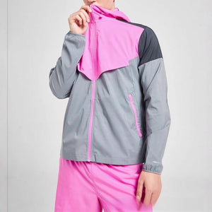 Man in a pink and grey colour block hooded sports jacket pulling the hood up to the chin