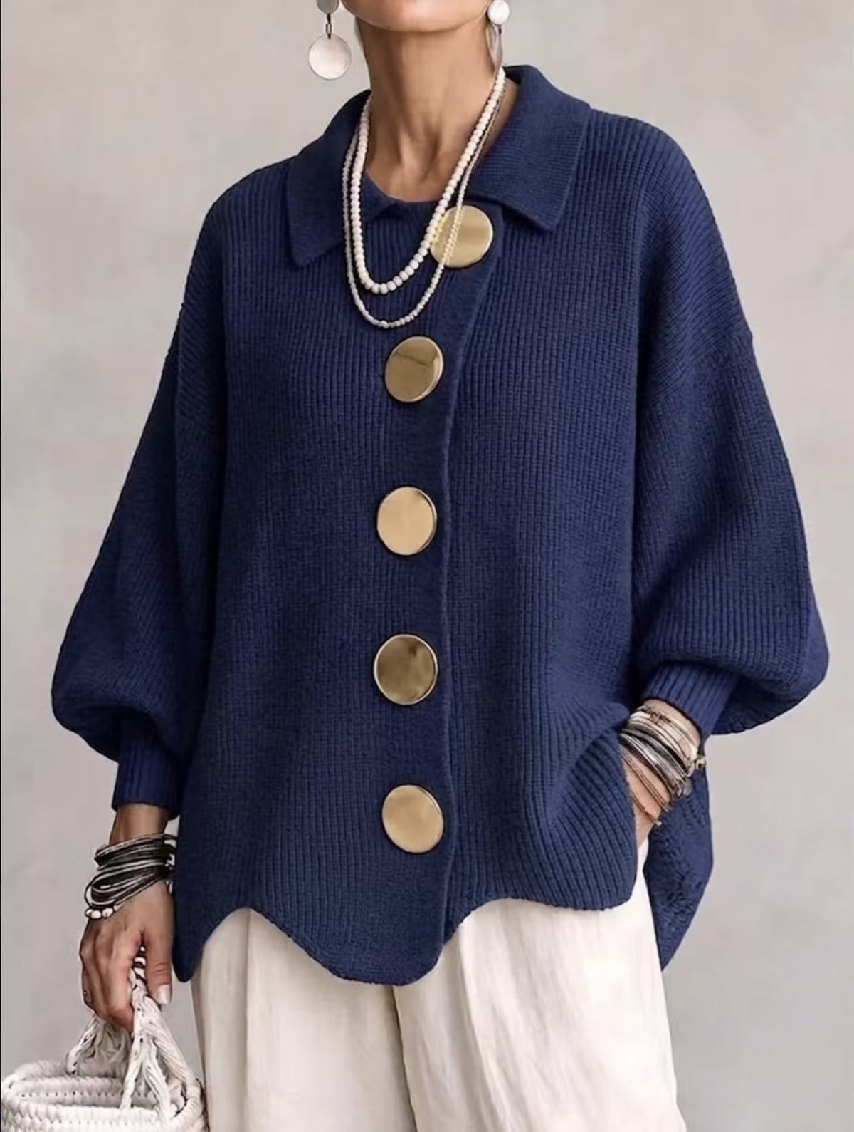 Woman in a navy loose knit top with a collar and large gold tone buttons, front view