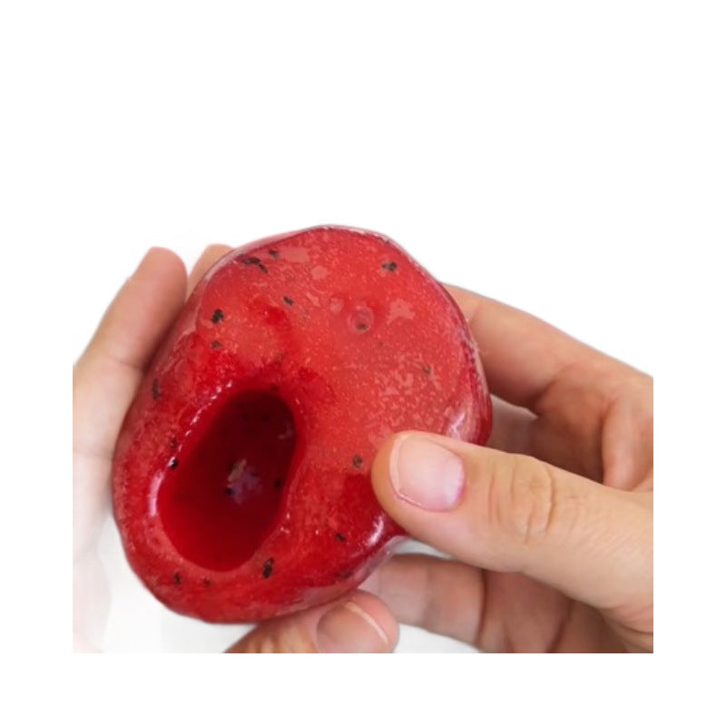 Thumb pressing a deep pit into the red gel squishy ball, wet looking translucent surface