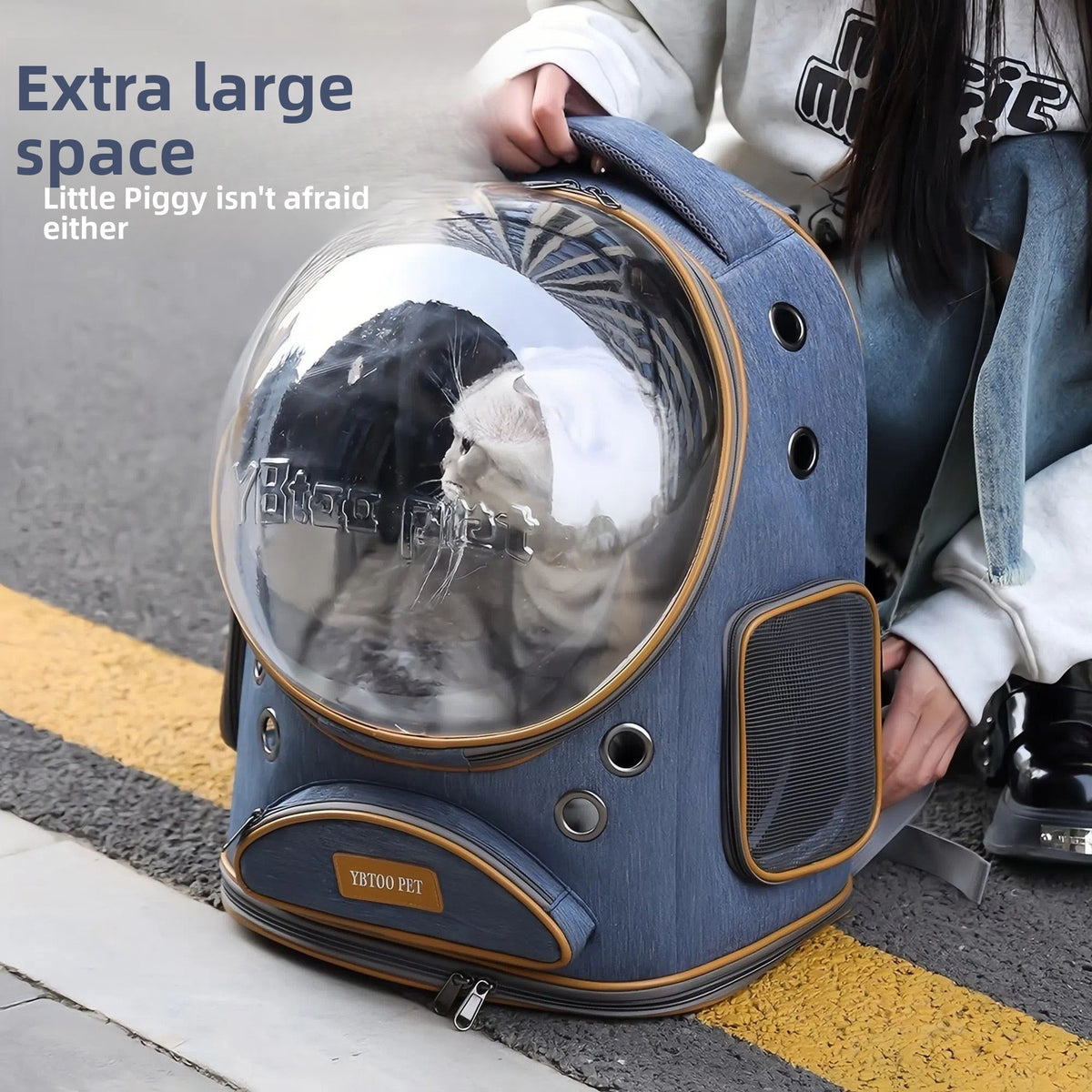 Denim blue space capsule cat carrier backpack with a cat inside the clear dome being lifted by the top handle