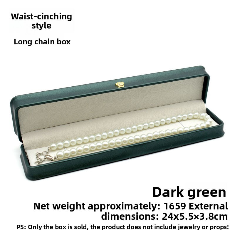 Open dark green crown clasp necklace box with a pearl necklace on the grey padded lining