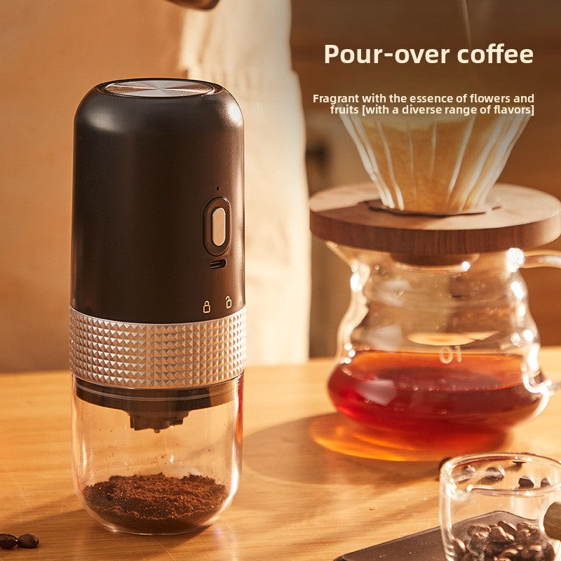 Black electric coffee grinder beside a pour-over dripper and glass server, grounds visible in the clear chamber