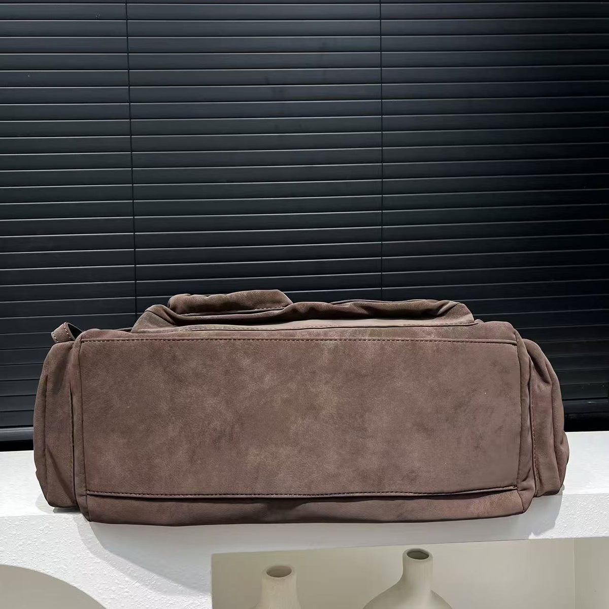 Underside of the mocha brown PU shoulder bag showing the flat stitched base panel and side pockets