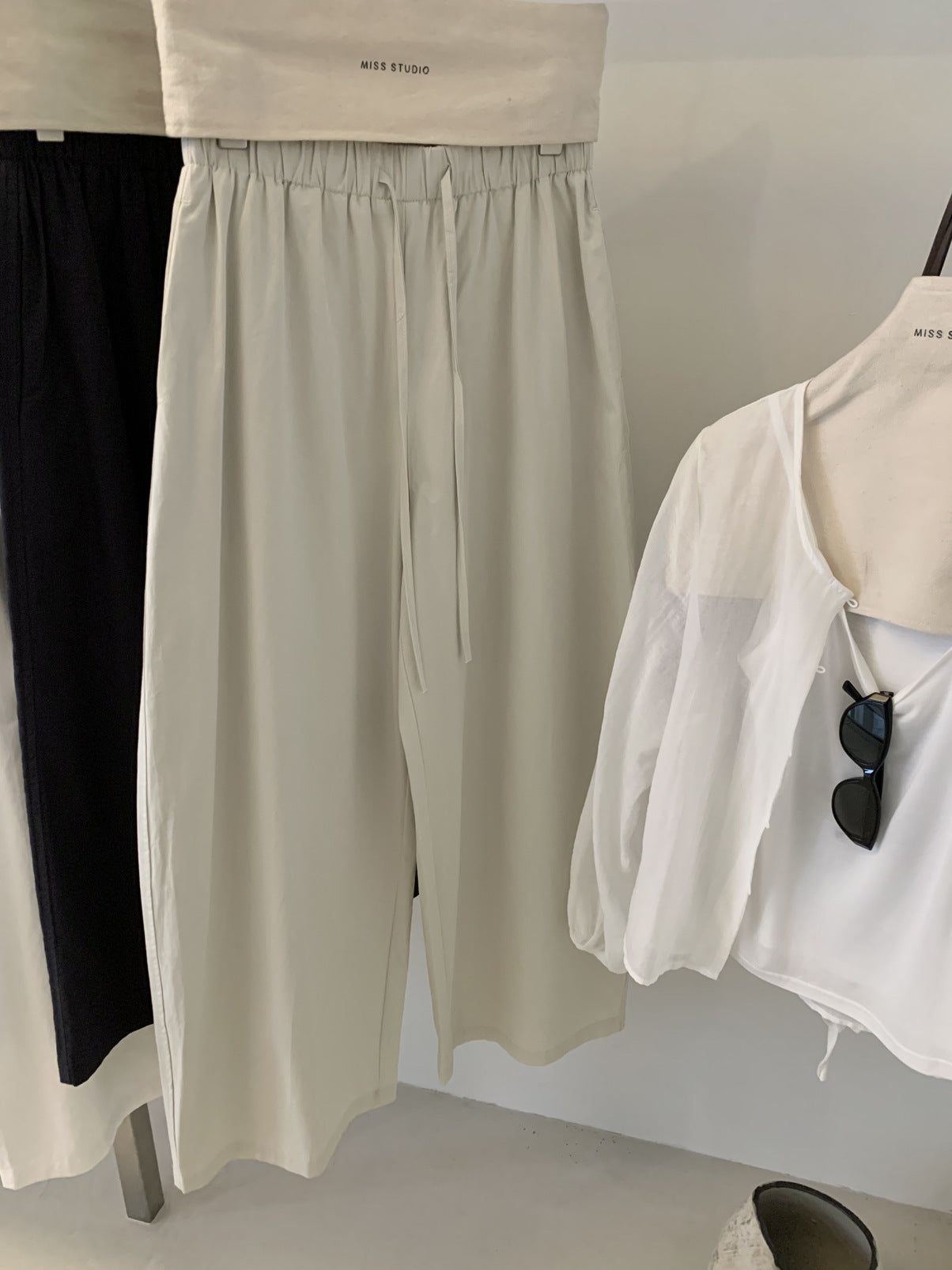 Greige cotton wide leg trousers on a hanger with self fabric drawstring tie