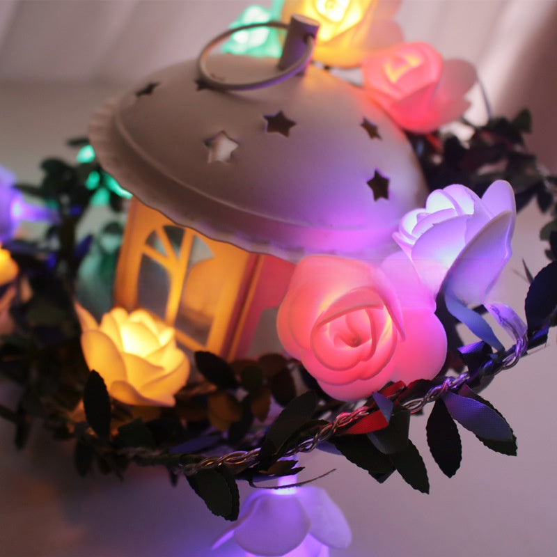 Colourful flower LED fairy string light on a green leaf vine with a warm glow, decorative photo