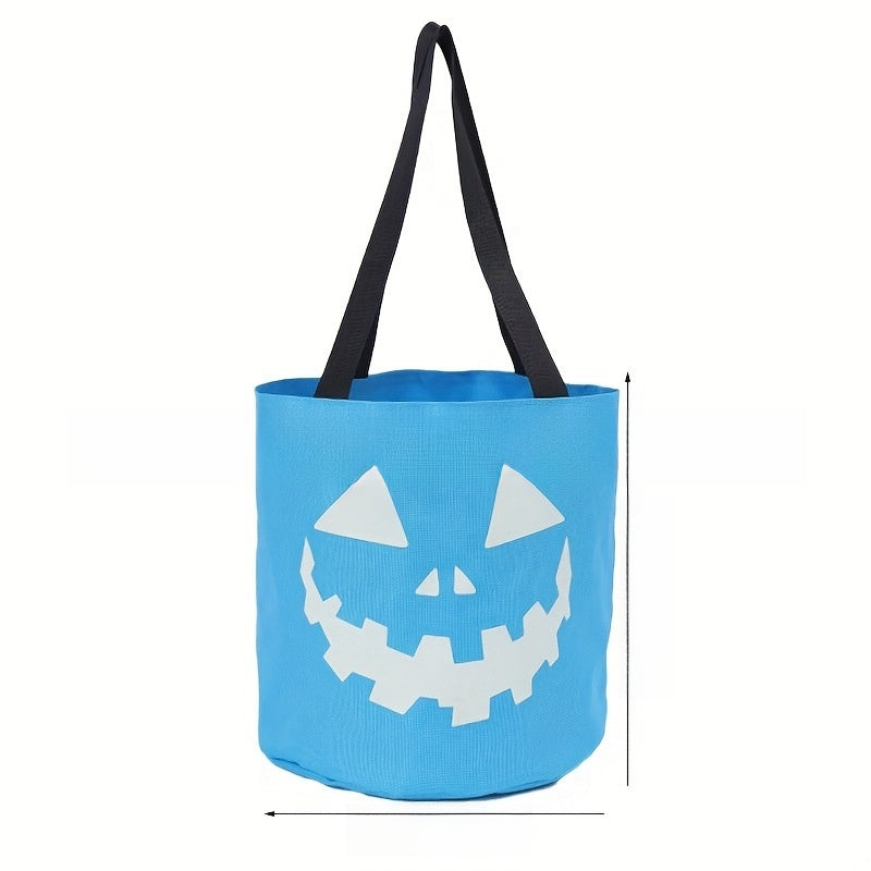 Blue canvas candy bucket with a printed pumpkin face and two fabric handles in daylight