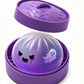 Purple ghost face squishy dumpling in a purple steamer basket with the lid off