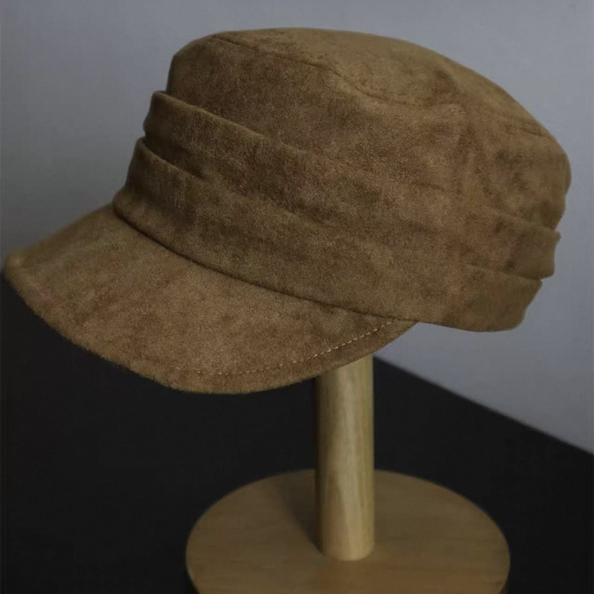 Cream vegan suede flat top cap held in hand, close view of the nap