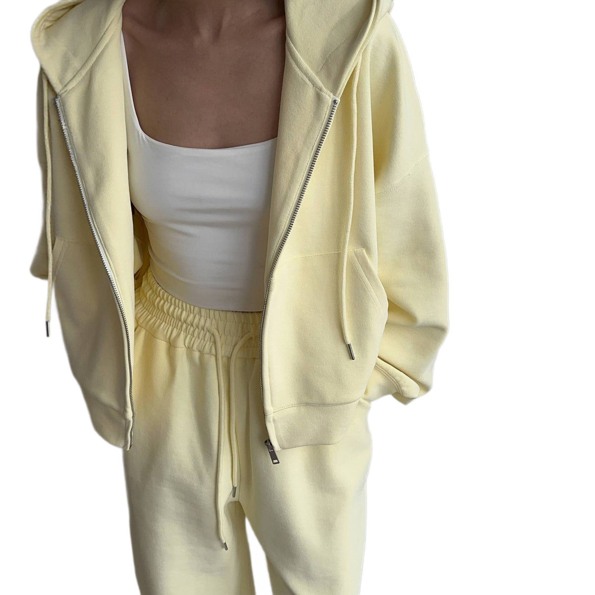 Close view of an open light yellow zip hoodie over a white top with the drawstring waist of matching trousers