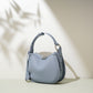 Dusty blue pebbled cowhide crescent bag at an angle with silver tone zip pulls, side ring and leather tab