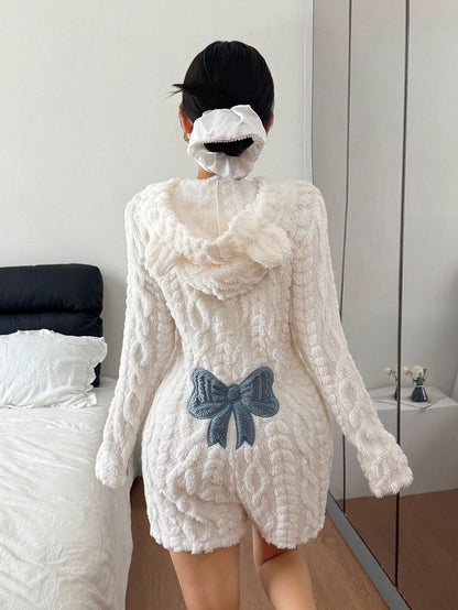 Back view of a white plush fleece hooded romper with bear ears and a blue bow patch, standing