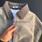 Hand holding the open zip front and pieced chest panel of the beige tie-dye PU leather jacket