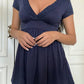Front view of the navy eyelet trim V-neck babydoll top with a flared peplum hem