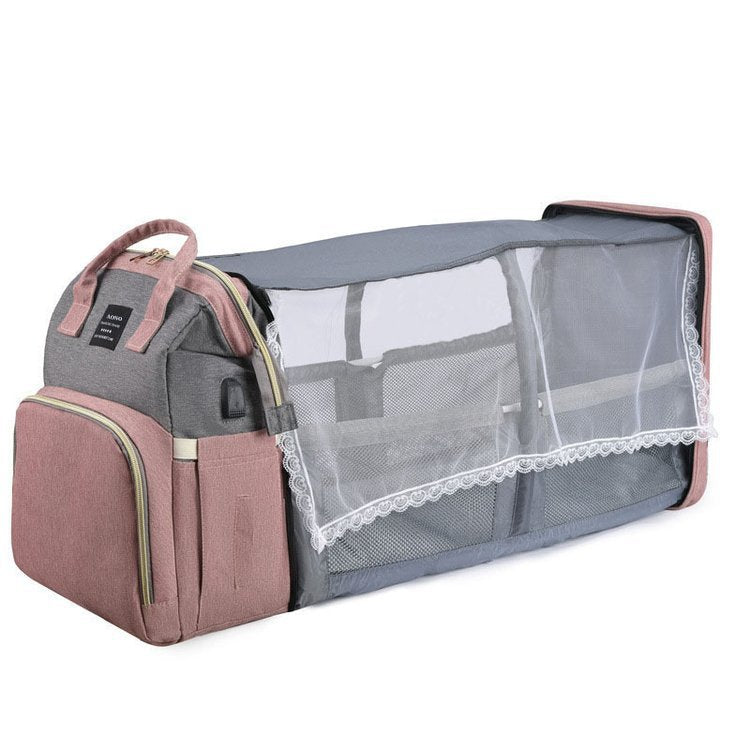 Pink and gray diaper backpack opened into a baby bed with mesh sides and a lace-trimmed mosquito net, side view