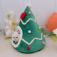 Green tree shaped pet den with a red bow and pompom baubles