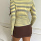 Back view of a light yellow and gray striped long sleeve top worn with a brown mini skirt