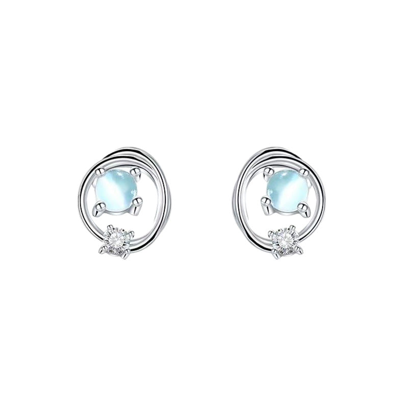 Studio close-up of both Saturn stud earrings, prong-set opalescent cabochon and small clear accent stone