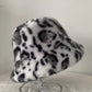 White and black leopard print plush bucket hat on a clear stand