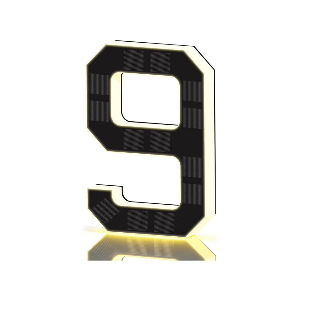 Black and gold solar LED house number sign, one character with a backlit warm outline, solar cells on the face