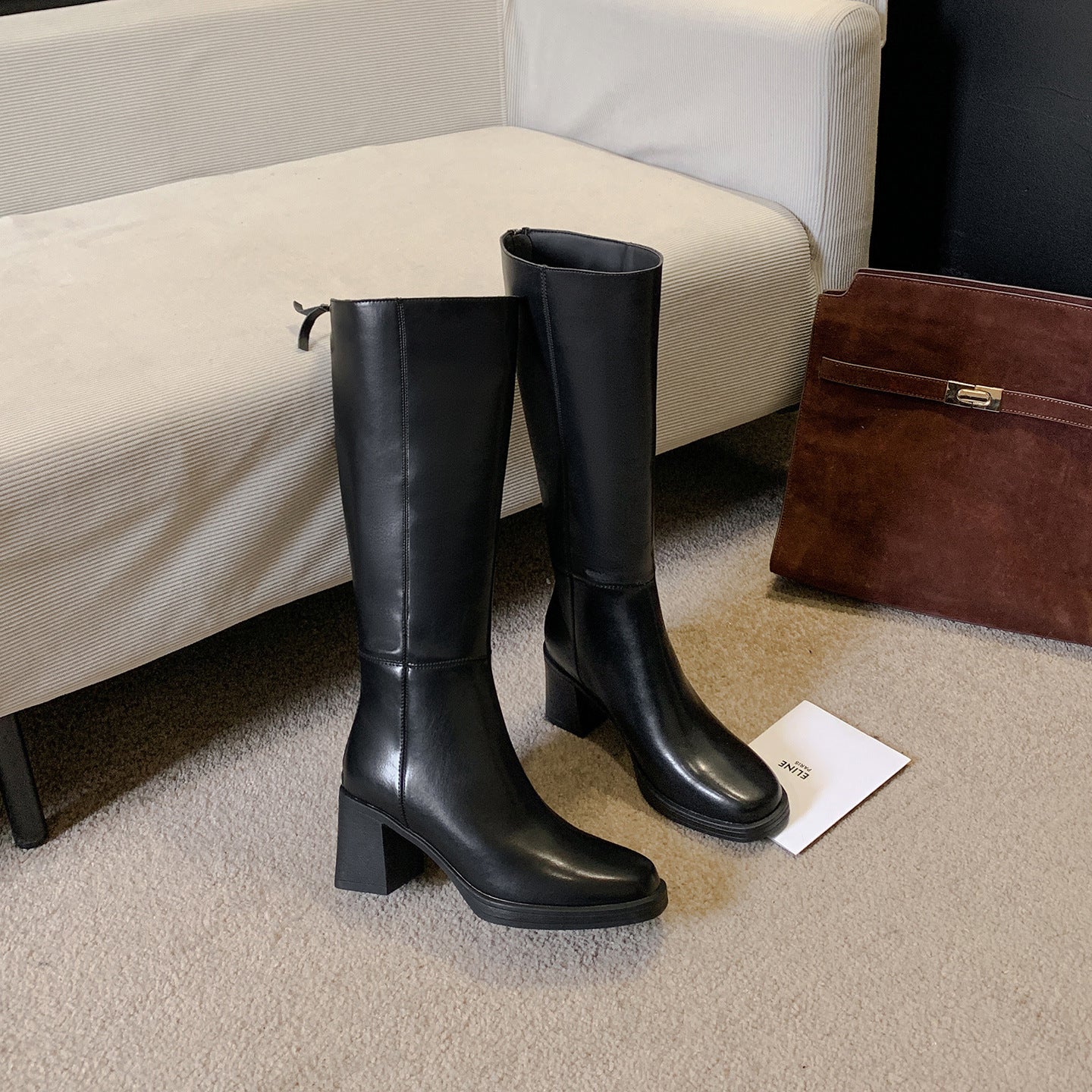Tall black cowhide leather boot showing the round toe and high shaft below the knee