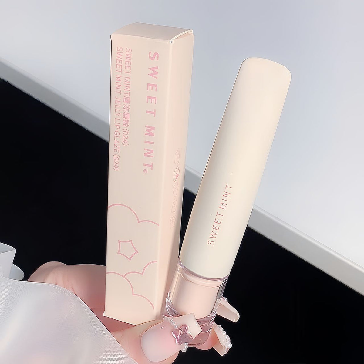 Cream lip glaze tube with a rounded clear applicator tip and a mirror shine gloss inside