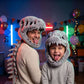 Gray plush dinosaur skull costume hood worn by an adult and a child at an indoor party with balloons