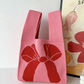 Cute jacquard knit handbag with a two tone motif and a wrist loop handle