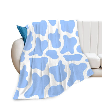 Cow print flannel blanket folded on a linen armchair beside a lamp