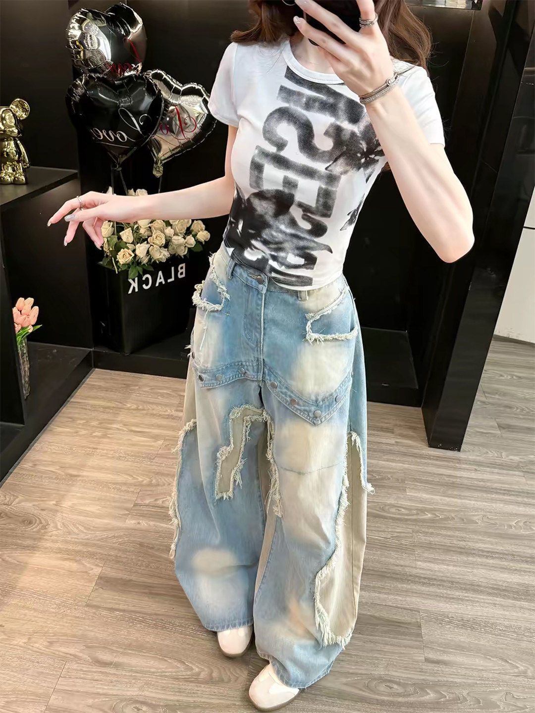 Frayed and whiskered raw edges on the light washed blue denim of wide leg baggy jeans, close view