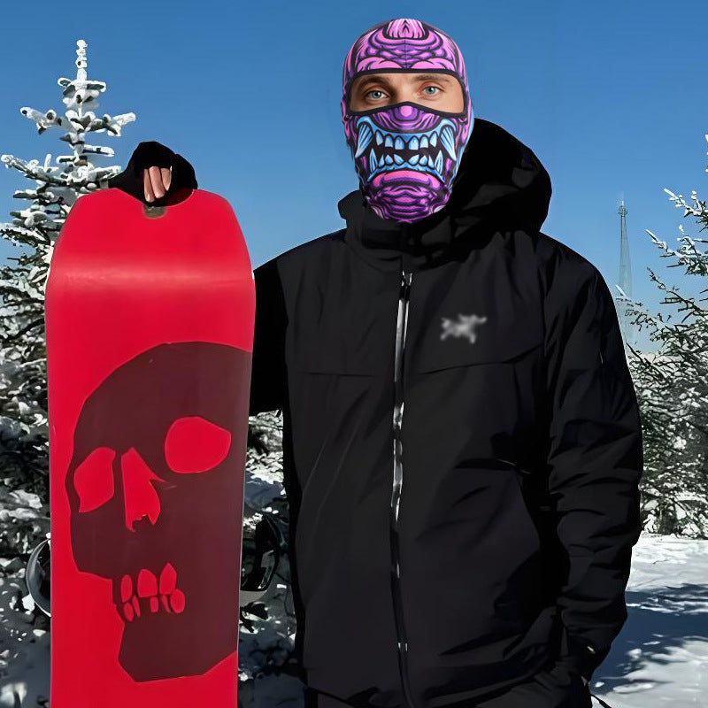 Snowboarder holding a red skull snowboard while wearing the purple monster print balaclava