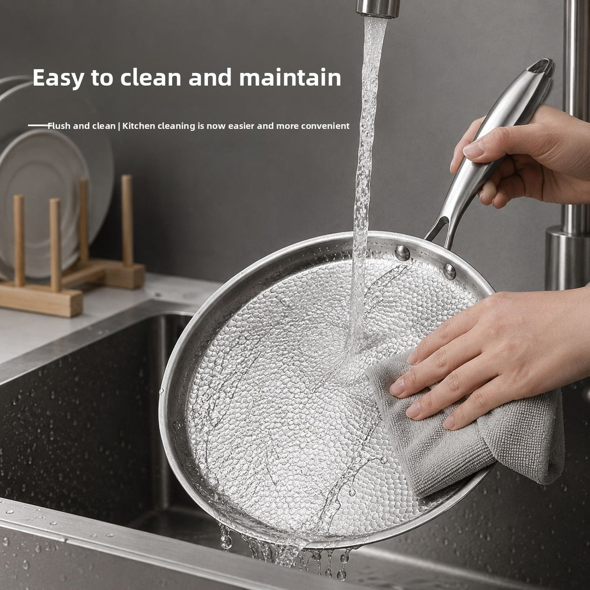 Hands washing a hammered flat pan under running tap water in a kitchen sink