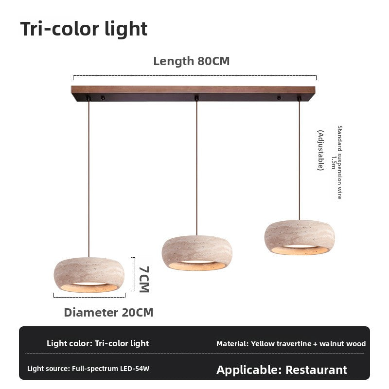 Travertine LED pendant lamp with a soft down glow over a side table and books