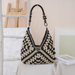 Woven straw shoulder bag carried on the shoulder with its flat strap resting evenly