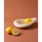 Glossy beige ceramic oval fruit bowl with lemons on a terracotta colored backdrop