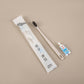 Beige straw toothbrush with charcoal bristles and a small toothpaste tube beside a frosted pouch