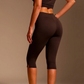 Three quarter back view of brown high-waisted capri leggings with a small slit at the hem