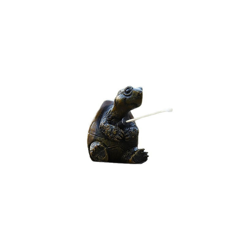 Small dark resin turtle figurine holding a fishing rod, photographed alone on white