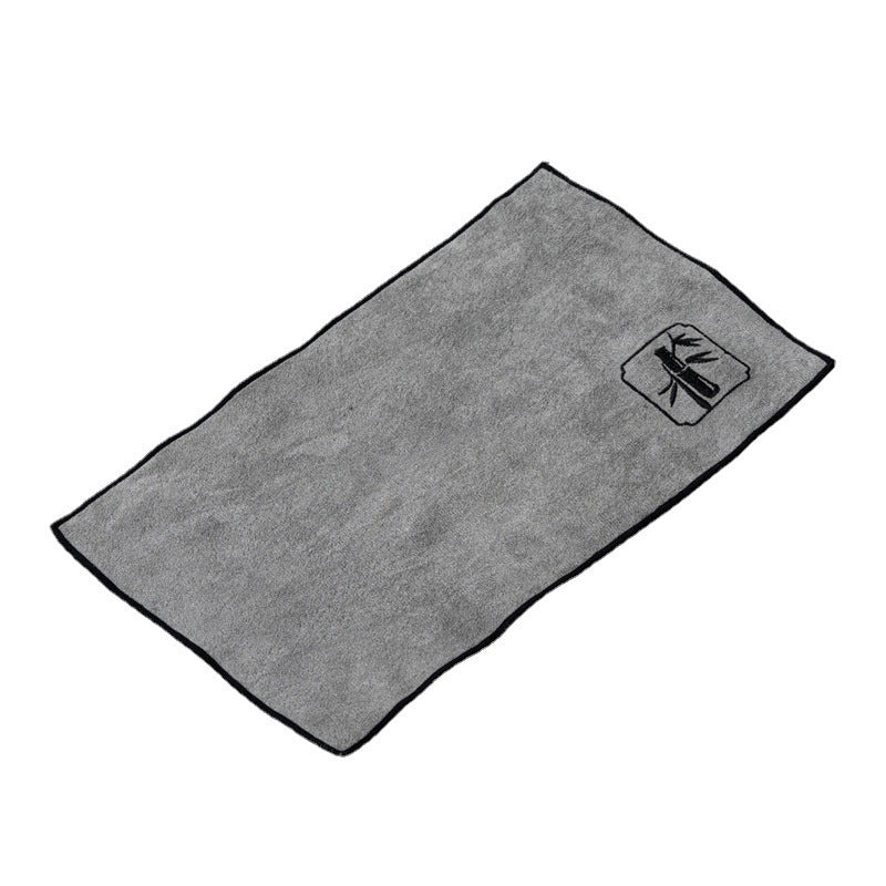 Light gray tea cloth with a bamboo motif embroidered in one corner on a white background