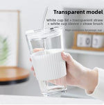 Glass straw cup with lid for coffee, scale reference next to a hand