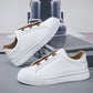 Pair of white slip-on low-top sneakers with white rubber sole resting against a metal case