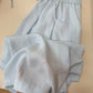 Yellow cotton linen casual pants draped over a round wooden board