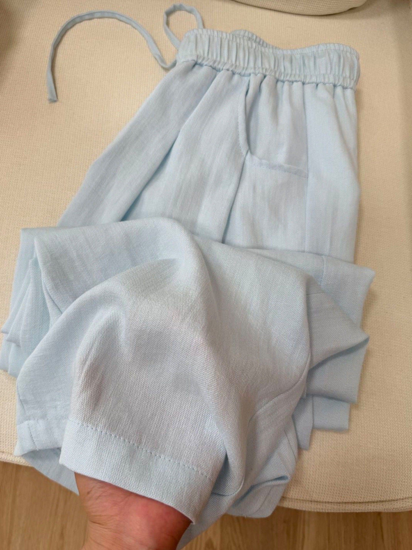 Yellow cotton linen casual pants draped over a round wooden board