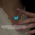 Blue butterfly pendant necklace glowing in the dark on a silver tone chain
