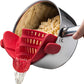 Red silicone clip-on pot strainer on a stainless steel pot draining pasta, water pouring from the spout