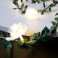 Decorative LED flower fairy string lights on a green leaf vine glowing warm, lifestyle photo
